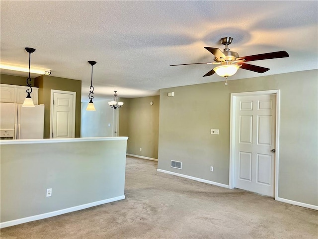 unfurnished room with baseboards, a ceiling fan, light carpet, a textured ceiling, and a chandelier