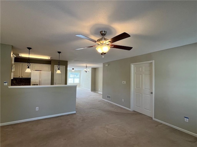 unfurnished living room featuring ceiling fan, light colored carpet, and baseboards