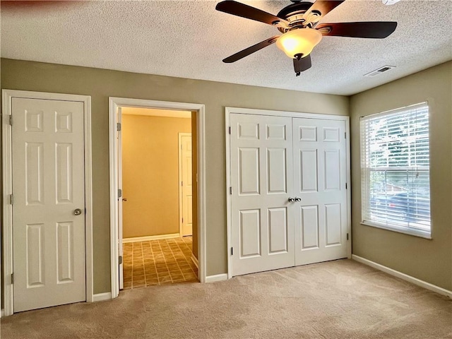 unfurnished bedroom with carpet floors, a textured ceiling, a closet, baseboards, and a ceiling fan