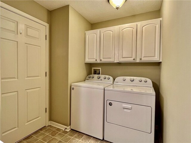 laundry area with independent washer and dryer, cabinet space, baseboards, and a textured ceiling