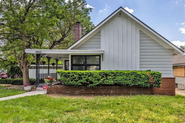2647 Minnesota Ave, Kansas City, KS 66102 - view of front of house with a front yard, board and batten siding, and a chimney