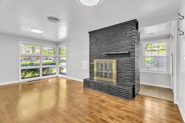 2647 Minnesota Ave, Kansas City, KS 66102 - unfurnished living room featuring wood finished floors, a glass covered fireplace, and baseboards