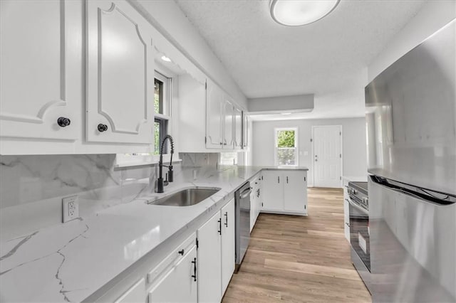 2647 Minnesota Ave, Kansas City, KS 66102 - kitchen featuring appliances with stainless steel finishes, a sink, white cabinets, light wood-style floors, and light stone countertops