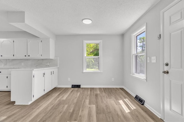 2647 Minnesota Ave, Kansas City, KS 66102 - unfurnished dining area featuring light wood-style floors, a textured ceiling, and baseboards