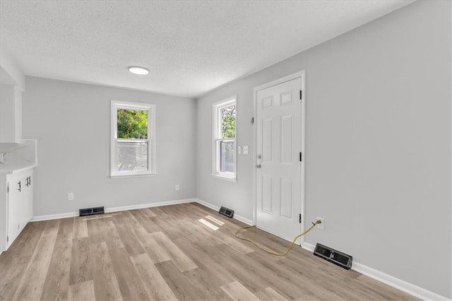 2647 Minnesota Ave, Kansas City, KS 66102 - unfurnished living room featuring light wood-style floors, a textured ceiling, and baseboards