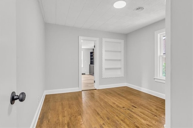 2647 Minnesota Ave, Kansas City, KS 66102 - unfurnished room with built in shelves, wood finished floors, and baseboards