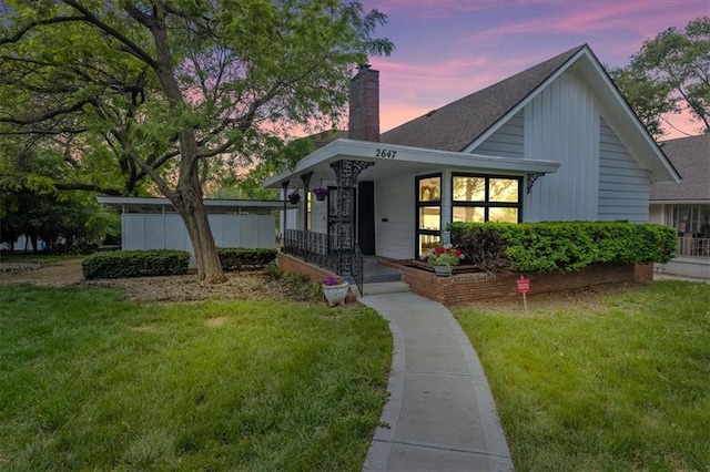 2647 Minnesota Ave, Kansas City, KS 66102 - view of front of home featuring a chimney, a porch, a lawn, a shingled roof, and board and batten siding