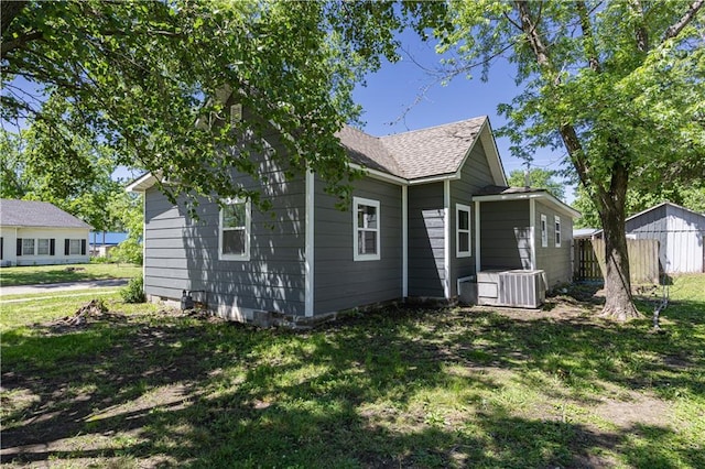 901 N 9th St, Neodesha, KS 66757 - back of property featuring cooling unit, a shingled roof, and a lawn