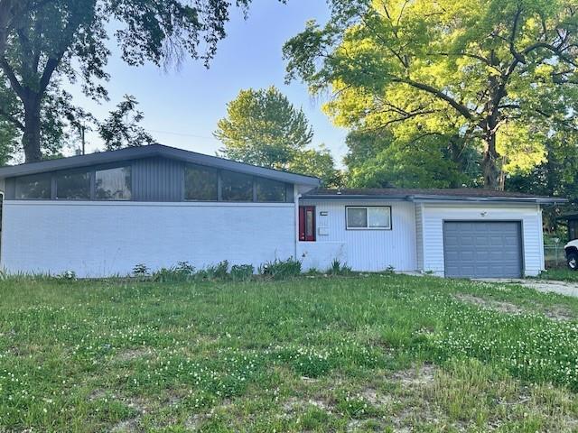 3602 Rowland Ave, Kansas City, KS 66104 - view of front of property with a garage, a front lawn, and a sunroom