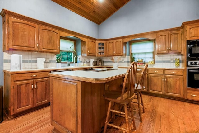 12808 Howe Dr, Leawood, KS 66209 - kitchen with black appliances, brown cabinets, light wood-type flooring, light countertops, and a kitchen island