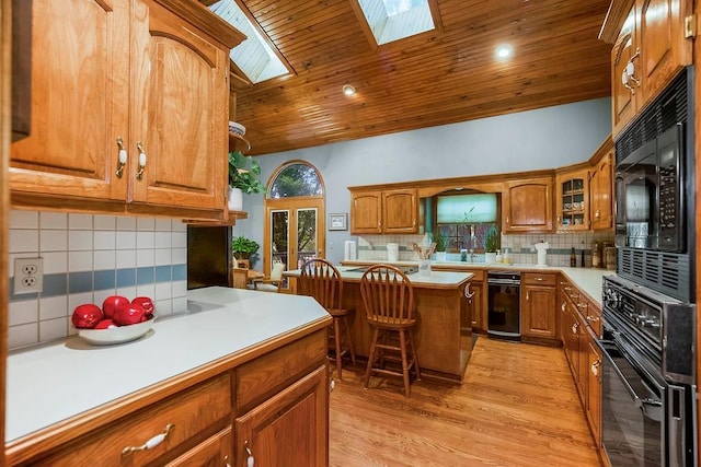 12808 Howe Dr, Leawood, KS 66209 - kitchen featuring black appliances, decorative backsplash, brown cabinets, a kitchen breakfast bar, and a skylight