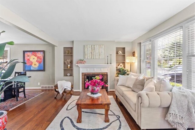 4111 W 69th St, Prairie Village, KS 66208 - living room with dark wood-style floors, built in shelves, baseboards, and a brick fireplace