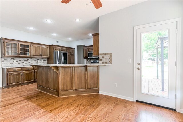 6402 W 147th Ter, Overland Park, KS 66223 - kitchen featuring stainless steel appliances, a ceiling fan, a kitchen bar, decorative backsplash, and glass insert cabinets