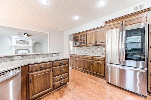 6402 W 147th Ter, Overland Park, KS 66223 - kitchen featuring stainless steel appliances, light wood-style flooring, ceiling fan, light stone countertops, and decorative backsplash