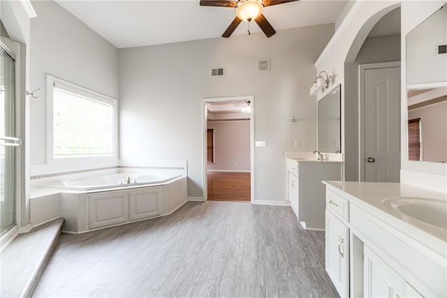 6402 W 147th Ter, Overland Park, KS 66223 - bathroom featuring ceiling fan, two vanities, a bath, a shower stall, and wood finished floors