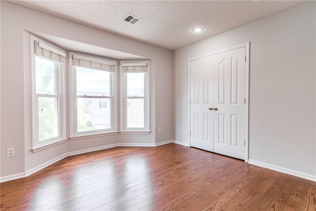 6402 W 147th Ter, Overland Park, KS 66223 - unfurnished bedroom with wood finished floors, a textured ceiling, baseboards, a closet, and recessed lighting
