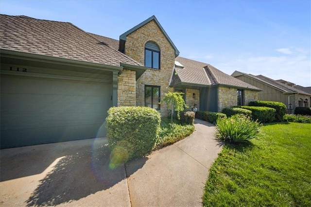 112 W 128th St, Kansas City, MO 64145 - view of front facade featuring stone siding, a front lawn, an attached garage, and concrete driveway