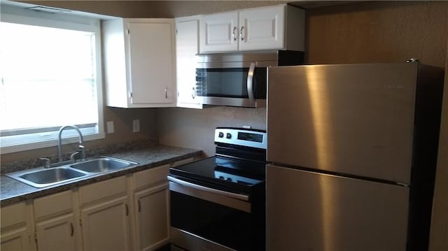 2219 E 75th St, Kansas City, MO 64132 - kitchen featuring appliances with stainless steel finishes, a sink, white cabinetry, and dark countertops