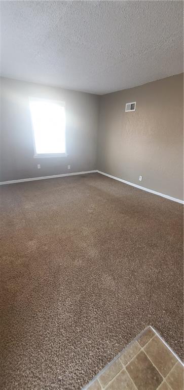 2219 E 75th St, Kansas City, MO 64132 - empty room with a textured ceiling, baseboards, and carpet