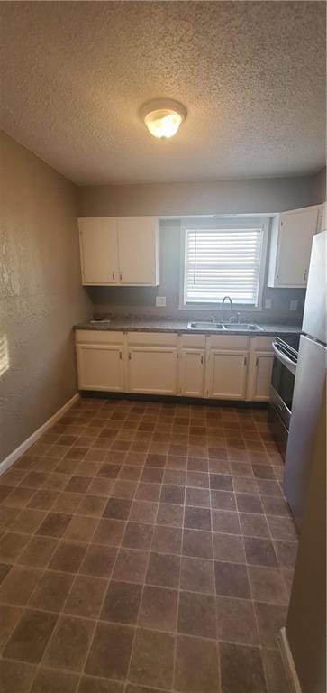 2219 E 75th St, Kansas City, MO 64132 - kitchen featuring a textured ceiling, a sink, electric range, baseboards, and white cabinets