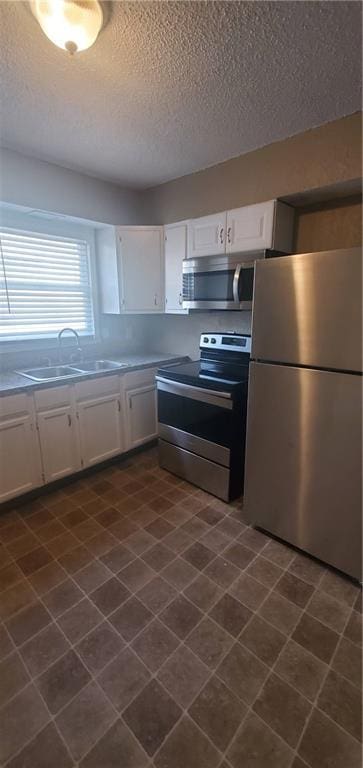 2219 E 75th St, Kansas City, MO 64132 - kitchen with stainless steel appliances, a sink, a textured ceiling, and white cabinetry
