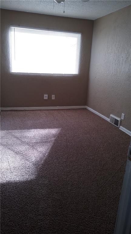 2219 E 75th St, Kansas City, MO 64132 - carpeted empty room with a textured ceiling and baseboards