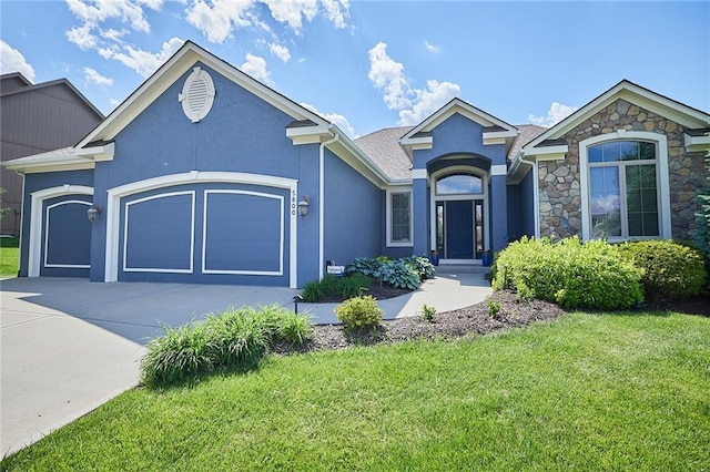 view of front of property featuring a garage, driveway, a front yard, stucco siding, and stone siding