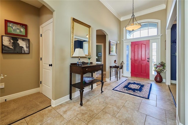 entrance foyer featuring arched walkways, crown molding, and baseboards