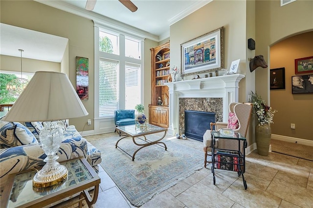 living room with ornamental molding, a high end fireplace, baseboards, plenty of natural light, and arched walkways