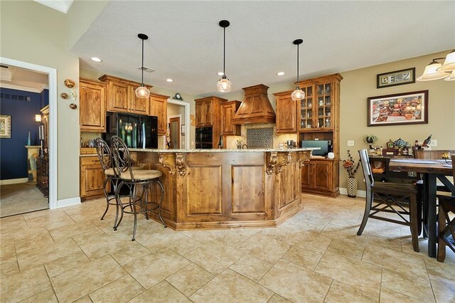kitchen with black fridge, brown cabinets, custom exhaust hood, a kitchen breakfast bar, and decorative backsplash