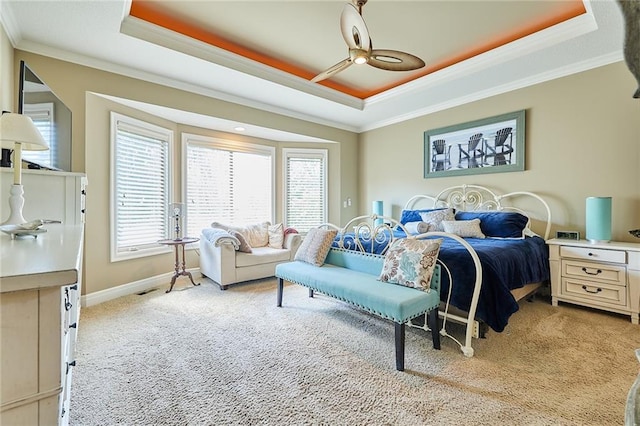 bedroom with a tray ceiling, ornamental molding, light colored carpet, ceiling fan, and baseboards