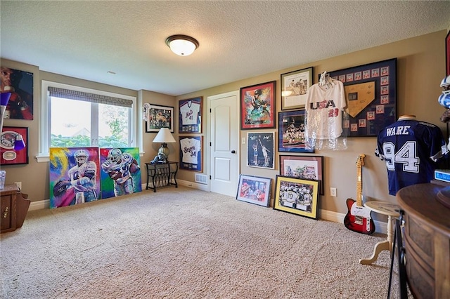 recreation room with carpet floors, a textured ceiling, and baseboards