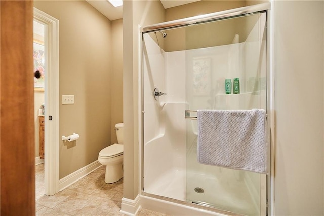 bathroom with a shower stall, toilet, and baseboards