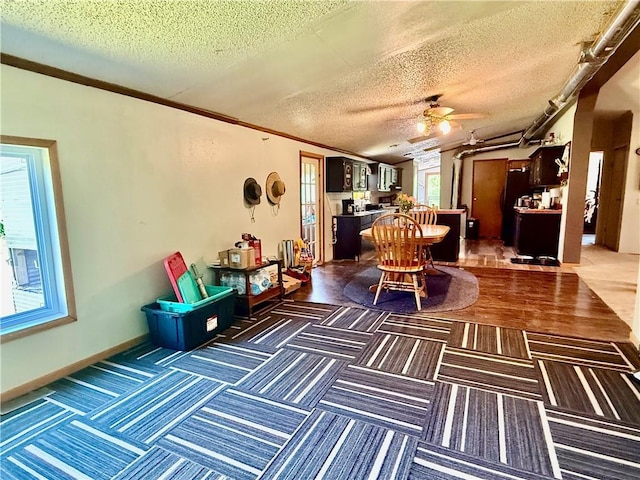 living area with ceiling fan, a textured ceiling, and ornamental molding
