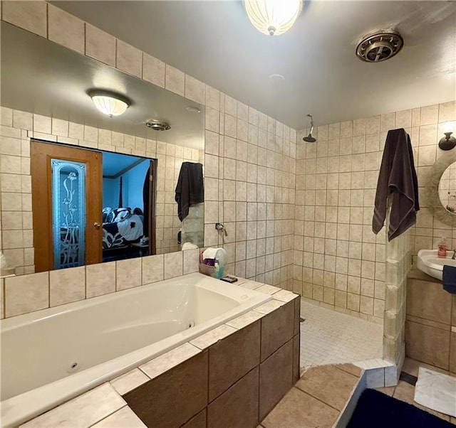 full bathroom with tile walls, tile patterned floors, walk in shower, a whirlpool tub, and a sink