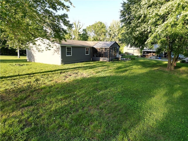 view of green lawn featuring a sunroom