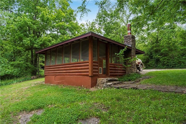 429 SE Lakeside Dr, Lacygne, KS 66040 - view of side of home with a sunroom, a chimney, log veneer siding, and a yard