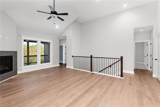 522 NW 110th St, Kansas City, MO 64155 - unfurnished living room featuring a ceiling fan, light wood-type flooring, a tile fireplace, high vaulted ceiling, and baseboards