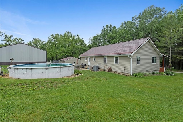 336 SE Zack Wheat Dr, Polo, MO 64671 - back of property featuring a lawn, metal roof, an outdoor pool, central AC, and view of wooded area