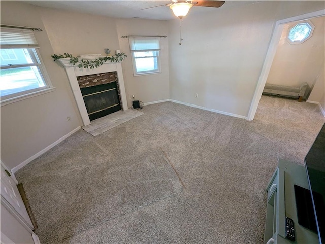 528 W Ashland St, Nevada, MO 64772 - unfurnished living room with ceiling fan, a tiled fireplace, baseboards, and carpet