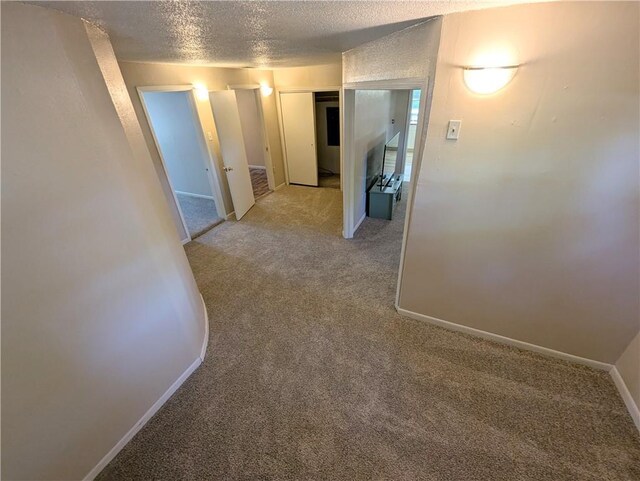 528 W Ashland St, Nevada, MO 64772 - hallway featuring light carpet, a textured ceiling, and baseboards