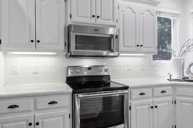 4612 Roberts St, Shawnee, KS 66226 - kitchen with appliances with stainless steel finishes, white cabinetry, backsplash, and light stone countertops