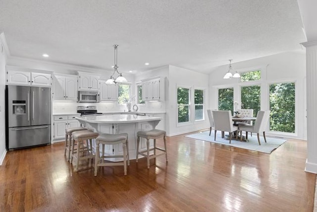 4612 Roberts St, Shawnee, KS 66226 - kitchen featuring appliances with stainless steel finishes, a chandelier, light countertops, white cabinets, and backsplash