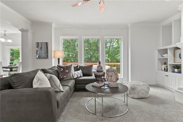 4612 Roberts St, Shawnee, KS 66226 - carpeted living room with ornamental molding, ceiling fan, a textured ceiling, a chandelier, and decorative columns