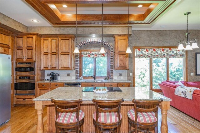 26650 W 100th Pl, Olathe, KS 66061 - kitchen featuring stainless steel appliances, brown cabinetry, light wood-type flooring, a sink, and a raised ceiling