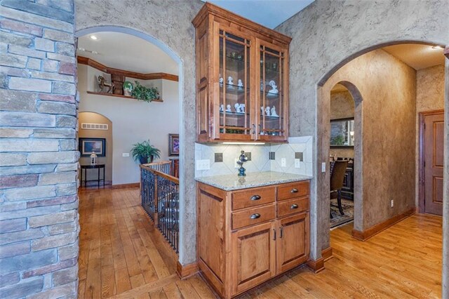 26650 W 100th Pl, Olathe, KS 66061 - bar area with light wood-style floors, arched walkways, decorative backsplash, and baseboards