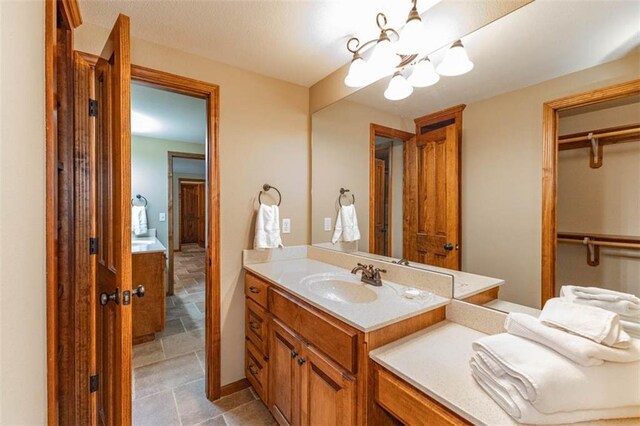 26650 W 100th Pl, Olathe, KS 66061 - bathroom featuring a chandelier, vanity, stone finish flooring, and a walk in closet