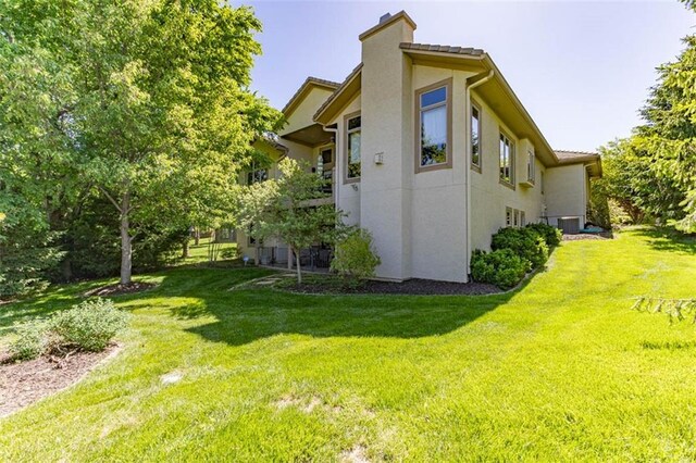 26650 W 100th Pl, Olathe, KS 66061 - view of side of property with a chimney, a lawn, stucco siding, and central air condition unit