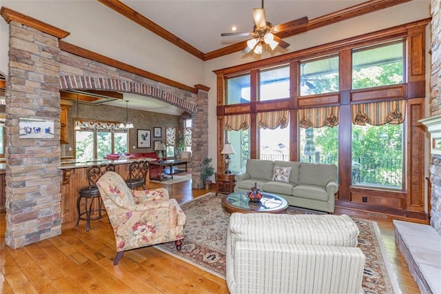 26650 W 100th Pl, Olathe, KS 66061 - living room with light wood-style flooring, crown molding, a ceiling fan, decorative columns, and arched walkways