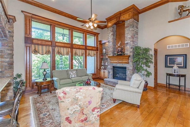 26650 W 100th Pl, Olathe, KS 66061 - living area with a stone fireplace, light wood-type flooring, a ceiling fan, a high ceiling, and arched walkways